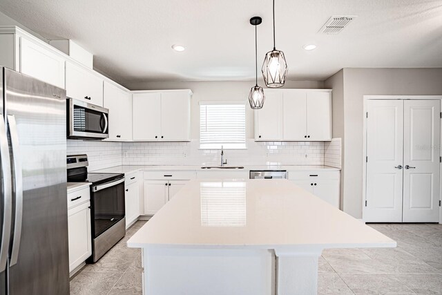 kitchen featuring a kitchen island, stainless steel appliances, sink, and white cabinets