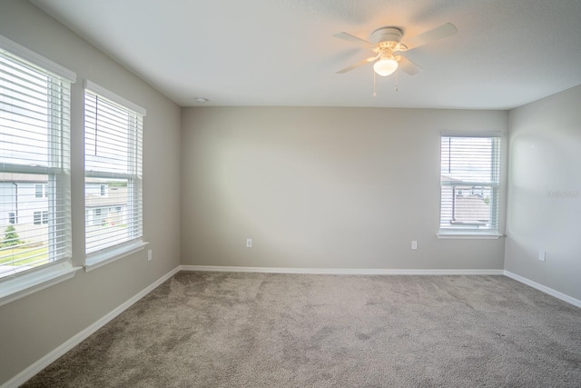 empty room with plenty of natural light, ceiling fan, and carpet floors