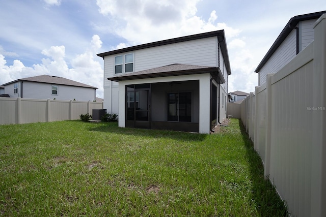 rear view of property featuring cooling unit, a lawn, and a sunroom