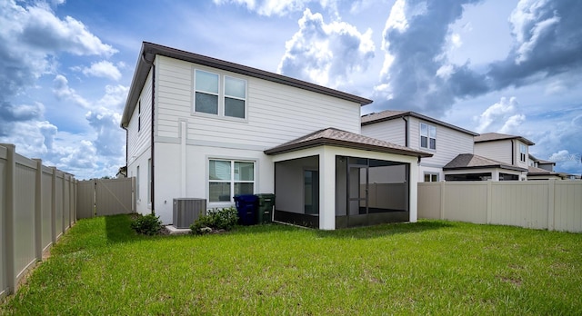 back of house featuring a sunroom, a yard, and central AC unit