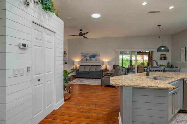 kitchen featuring decorative light fixtures, wood-type flooring, light stone counters, sink, and ceiling fan