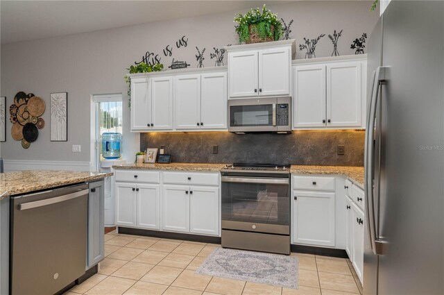 kitchen featuring appliances with stainless steel finishes, white cabinetry, light stone counters, and tasteful backsplash