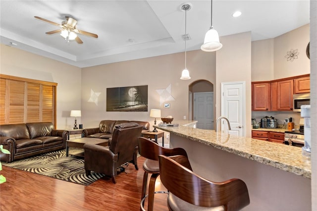 kitchen featuring appliances with stainless steel finishes, ceiling fan, wood-type flooring, and a breakfast bar