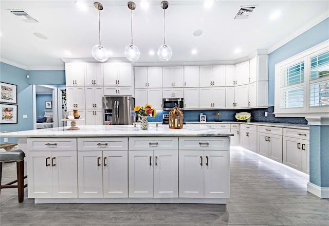 kitchen featuring a center island, decorative light fixtures, stainless steel appliances, white cabinetry, and tasteful backsplash