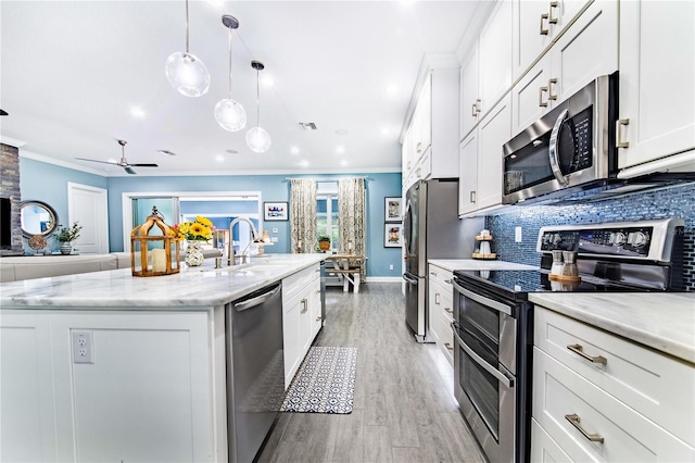 kitchen with a kitchen island with sink, appliances with stainless steel finishes, light stone counters, and ceiling fan