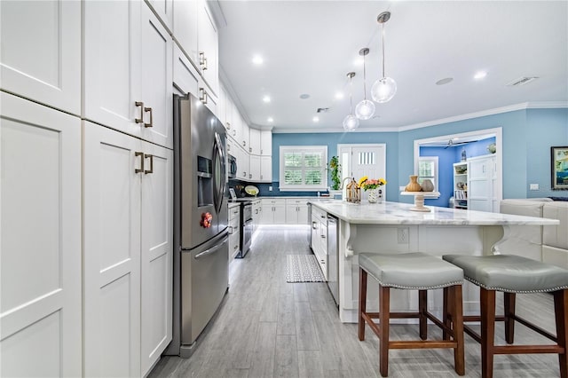 kitchen with a kitchen island, a kitchen breakfast bar, appliances with stainless steel finishes, light wood-type flooring, and white cabinets