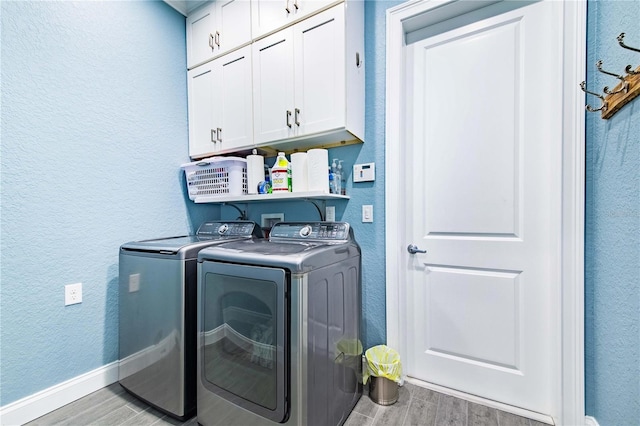 laundry area with light wood-type flooring, cabinets, and washer and dryer