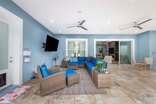 living room with ceiling fan and a stone fireplace