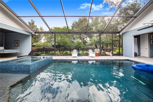 view of pool with a patio area, glass enclosure, and an in ground hot tub