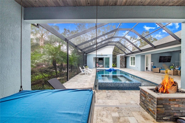 view of pool featuring a fire pit, glass enclosure, a patio, and an in ground hot tub