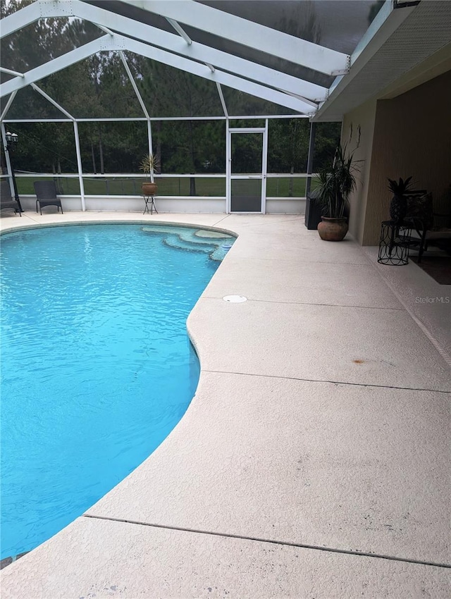 view of pool with glass enclosure and a patio