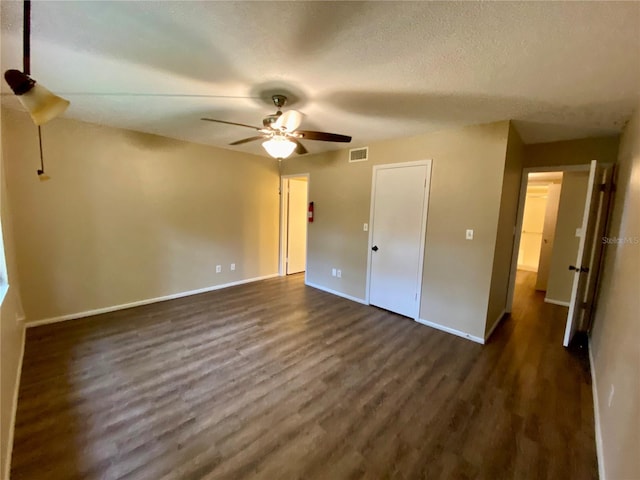 unfurnished bedroom with dark wood-type flooring, a textured ceiling, and ceiling fan