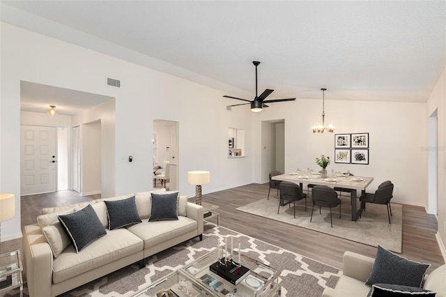 living room with ceiling fan with notable chandelier, lofted ceiling, and wood-type flooring