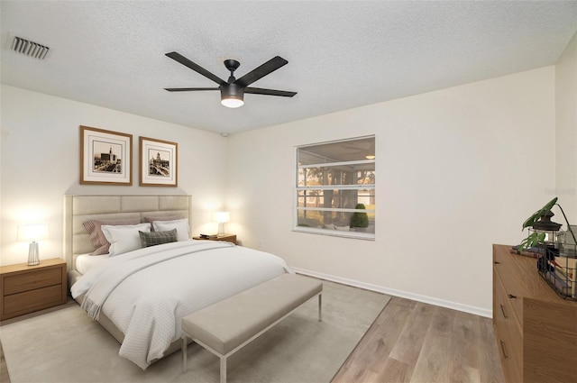 bedroom with a textured ceiling, light hardwood / wood-style flooring, and ceiling fan