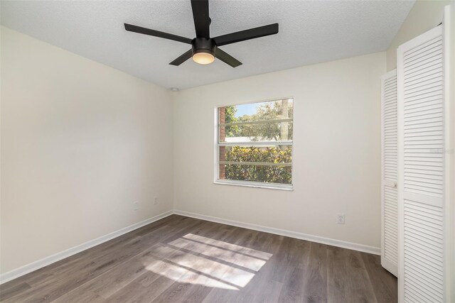 unfurnished bedroom with a textured ceiling, ceiling fan, dark hardwood / wood-style floors, and a closet