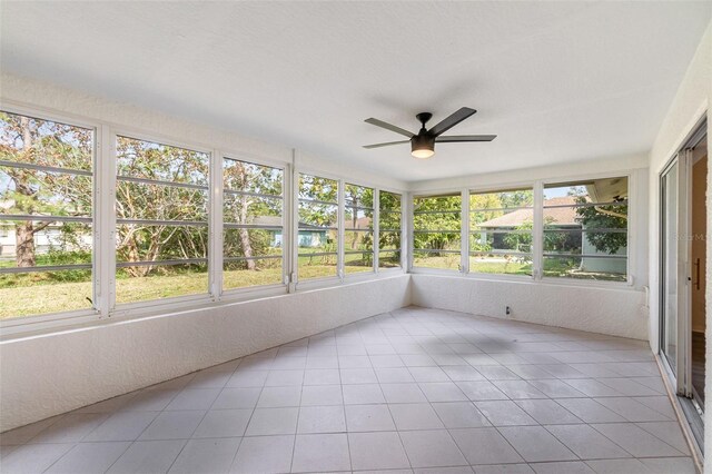 unfurnished sunroom featuring ceiling fan and a wealth of natural light