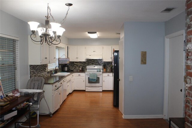 kitchen featuring black refrigerator, wood-type flooring, white range with electric stovetop, white cabinets, and tasteful backsplash