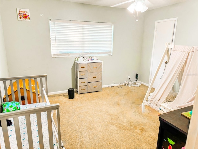 carpeted bedroom featuring ceiling fan and a crib