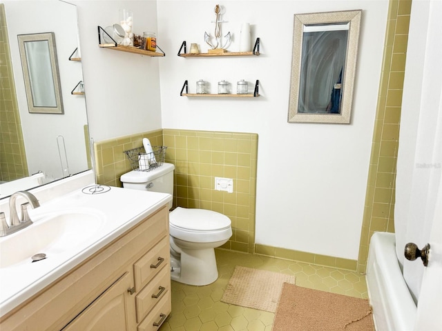 bathroom with vanity, a wainscoted wall, tile patterned flooring, tile walls, and toilet