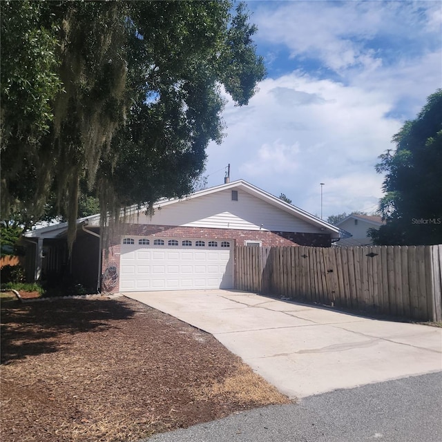 view of front of property with an attached garage, fence, brick siding, and driveway