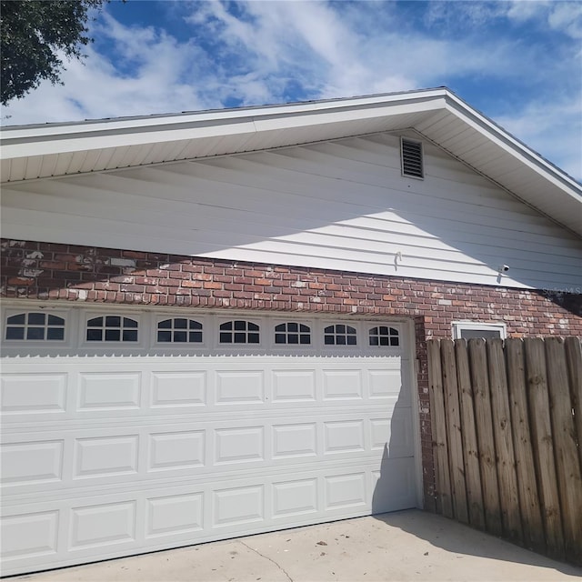 garage featuring concrete driveway and fence