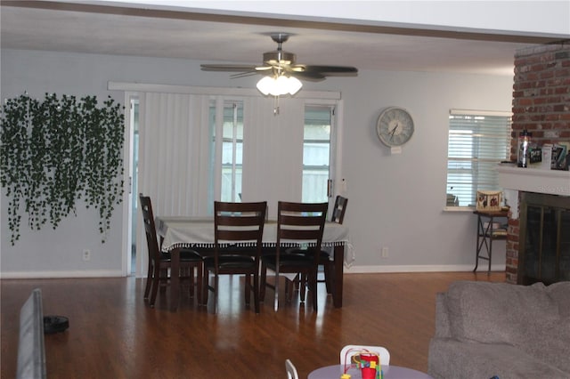 dining space featuring a brick fireplace, dark hardwood / wood-style floors, and ceiling fan