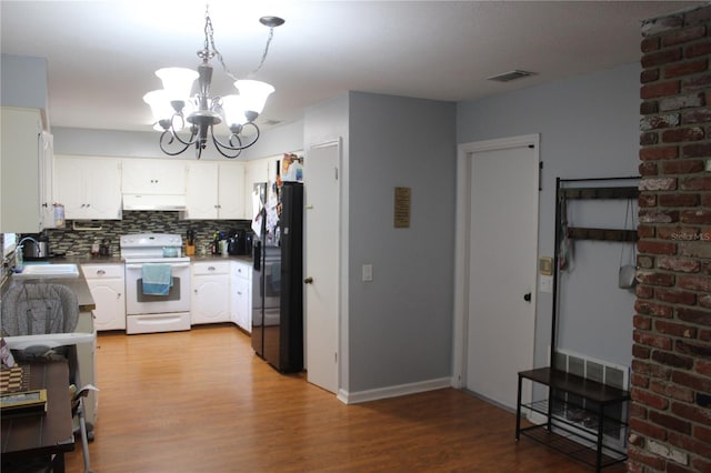 kitchen with a chandelier, under cabinet range hood, freestanding refrigerator, white range with electric stovetop, and a sink