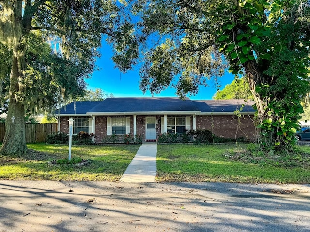 single story home with brick siding, a front yard, and fence