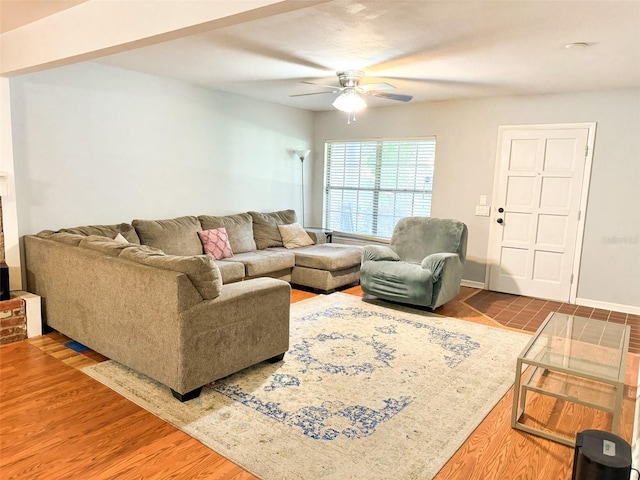 living area with baseboards, wood finished floors, and ceiling fan