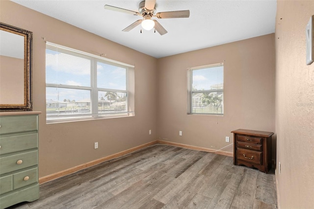 unfurnished bedroom with multiple windows, hardwood / wood-style flooring, and ceiling fan