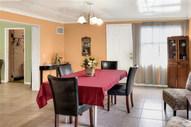 dining area featuring an inviting chandelier, crown molding, and light tile patterned floors