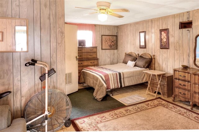 bedroom with carpet, wood walls, and ceiling fan