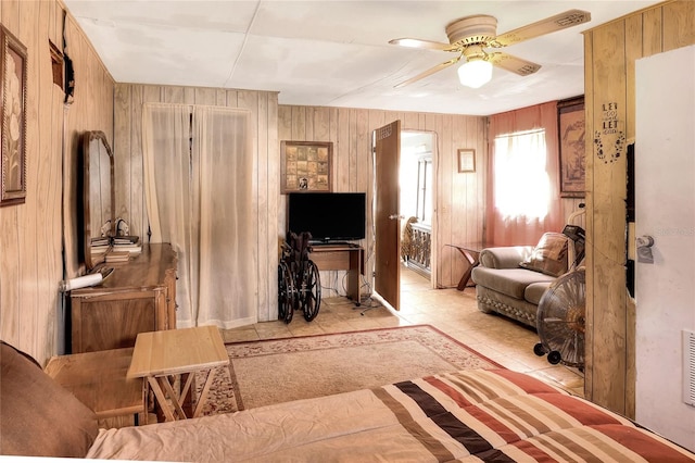 living room featuring wooden walls, ceiling fan, and light tile patterned floors