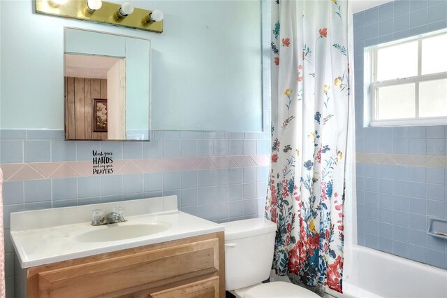 full bathroom with tile walls, shower / tub combo, vanity, and toilet