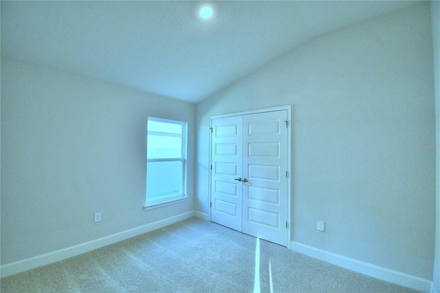 unfurnished bedroom featuring a closet, carpet flooring, and vaulted ceiling