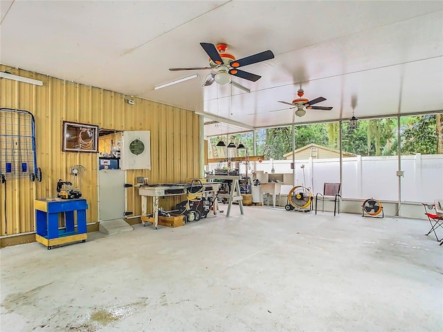 garage featuring ceiling fan and wood walls