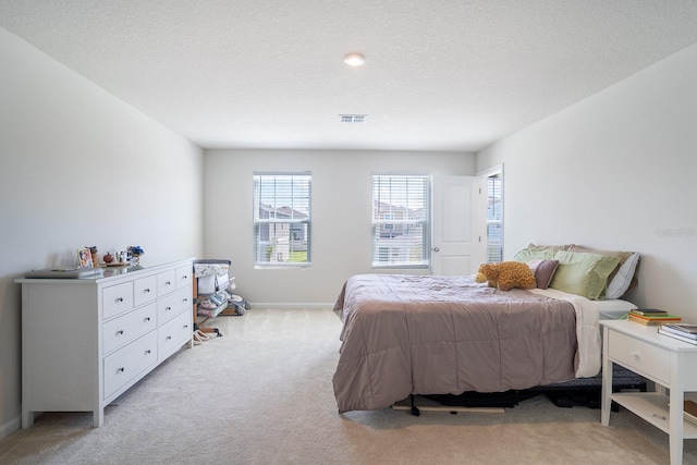 bedroom featuring light carpet and a textured ceiling