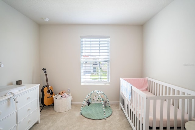 carpeted bedroom featuring a textured ceiling and a crib