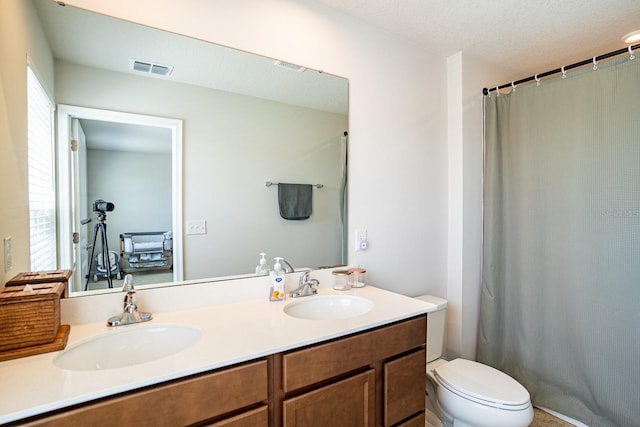 bathroom featuring vanity, toilet, walk in shower, and a textured ceiling