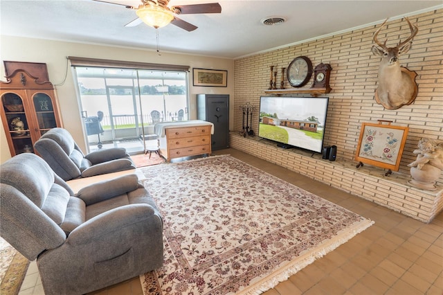 living room with crown molding, brick wall, tile patterned floors, and ceiling fan