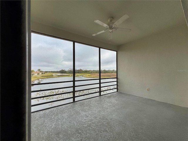 unfurnished sunroom featuring a water view and ceiling fan