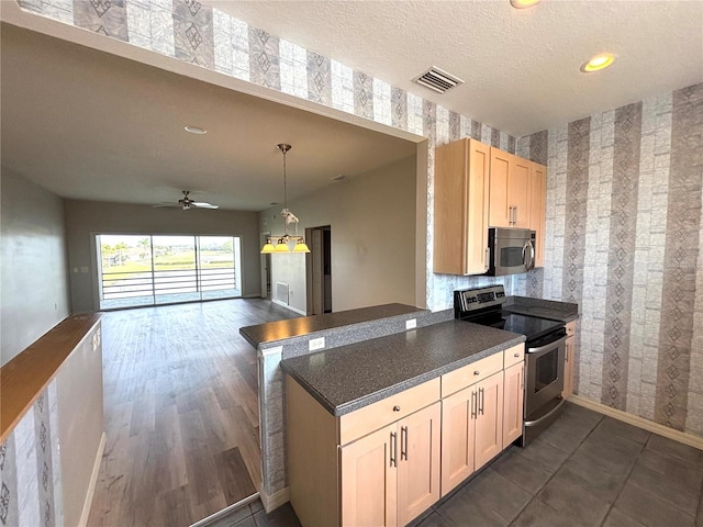 kitchen with stainless steel appliances, a textured ceiling, kitchen peninsula, and light brown cabinets