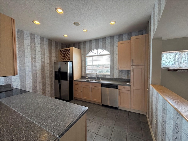 kitchen with stainless steel appliances, sink, dark tile patterned flooring, a textured ceiling, and light brown cabinetry