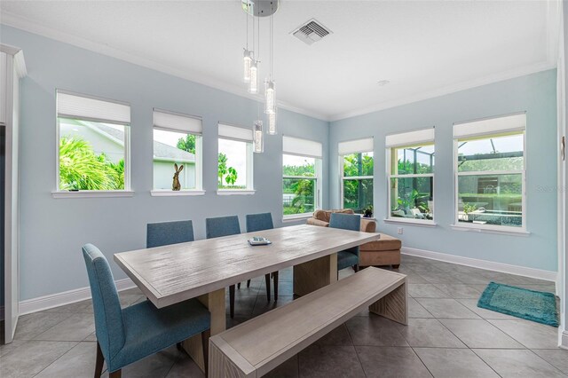 tiled dining room with crown molding and a healthy amount of sunlight