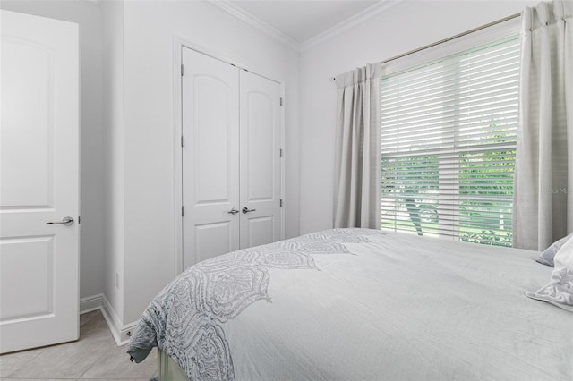 bedroom featuring a closet, light tile patterned flooring, and ornamental molding