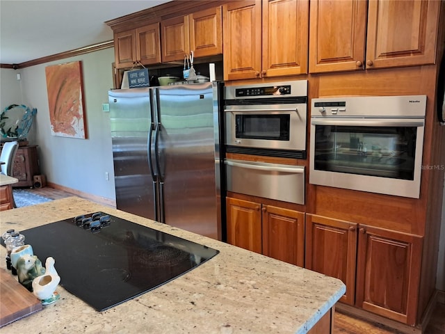 kitchen with light stone countertops, crown molding, appliances with stainless steel finishes, and light hardwood / wood-style flooring