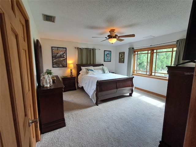 bedroom featuring a textured ceiling, light colored carpet, and ceiling fan