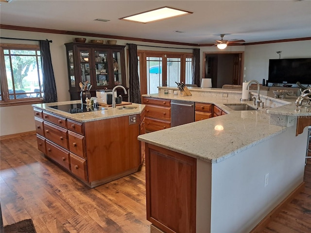 kitchen featuring hardwood / wood-style floors, dishwasher, a large island with sink, sink, and black electric cooktop