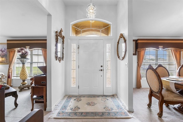 carpeted foyer featuring a wealth of natural light and a chandelier