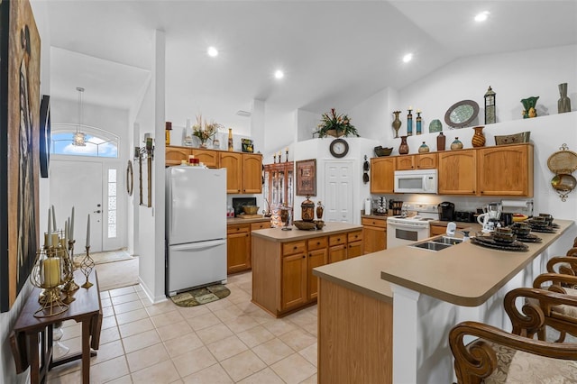 kitchen with high vaulted ceiling, white appliances, light tile patterned floors, kitchen peninsula, and a breakfast bar area